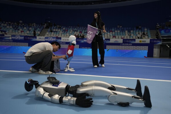 A worker prepares a robot before the opening ceremony of The World Humanoid Robot Games held in Beijing, China, Thursday, Aug. 14, 2025. (AP Photo/Ng Han Guan)