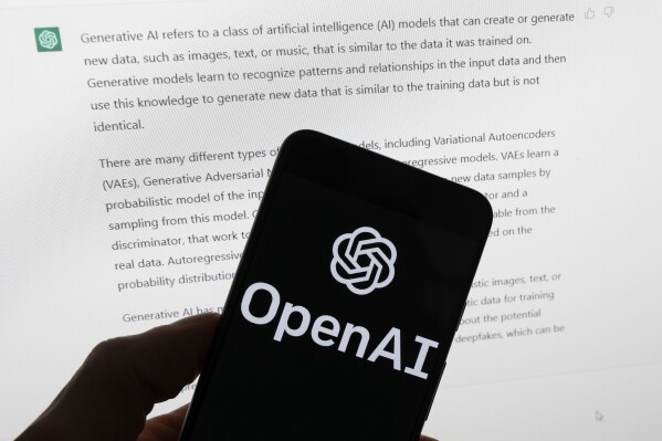The OpenAI logo is seen on a mobile phone in front of a computer screen displaying output from ChatGPT, March 21, 2023, in Boston. (AP Photo/Michael Dwyer, File)