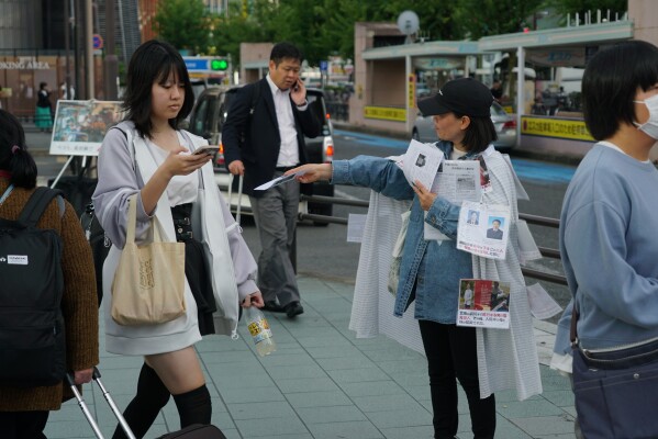 Yang Caiying, who is living in exile in Japan, shows a leaflet protesting Chinese state repression of her family to pedestrians in Nagoya, Japan, Friday, May 17, 2024.