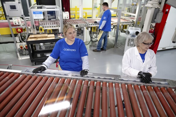 Quality control employees watch glass lengths in Corning