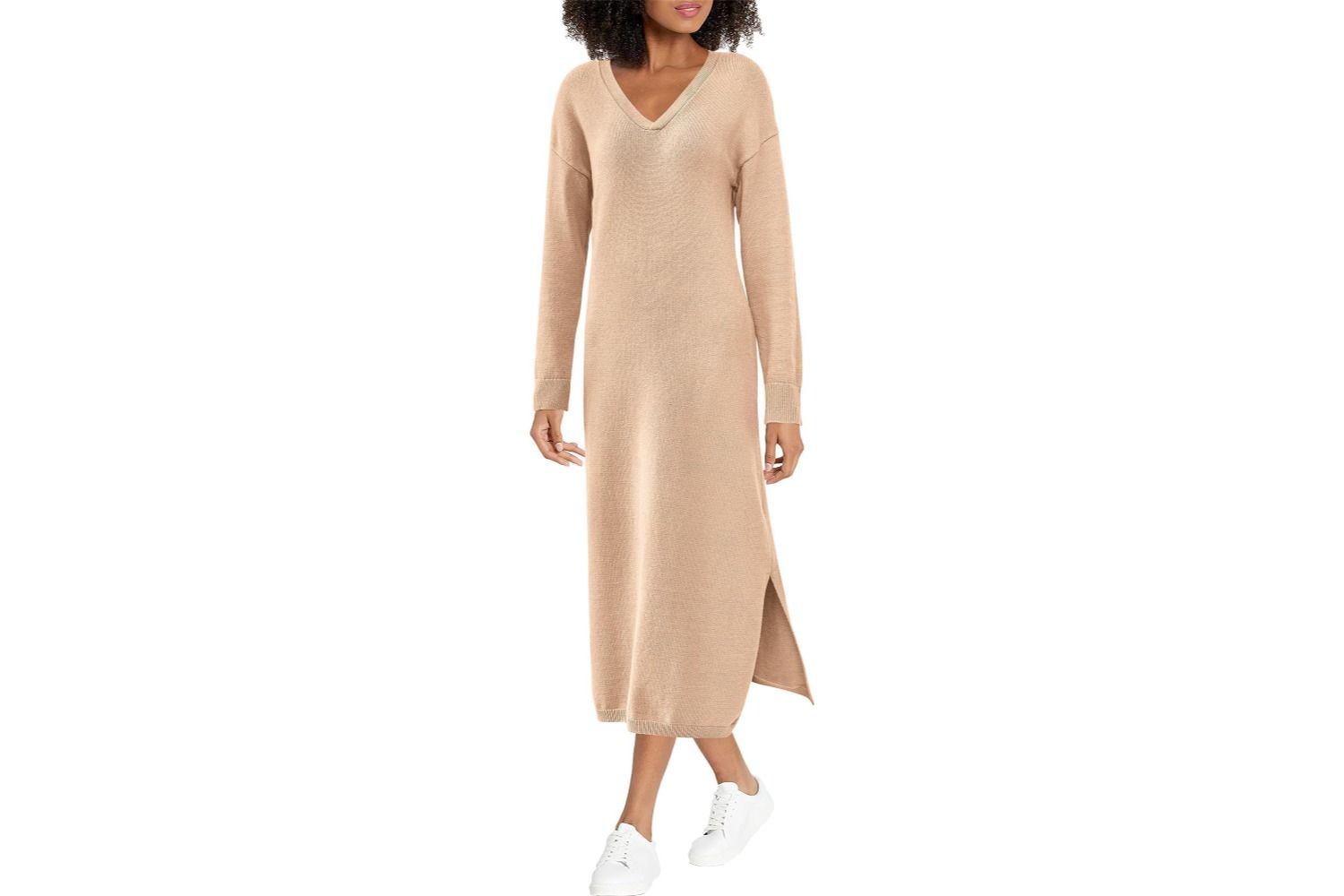 A model wearing a long Vneck sweater dress with a side slit paired with white sneakers