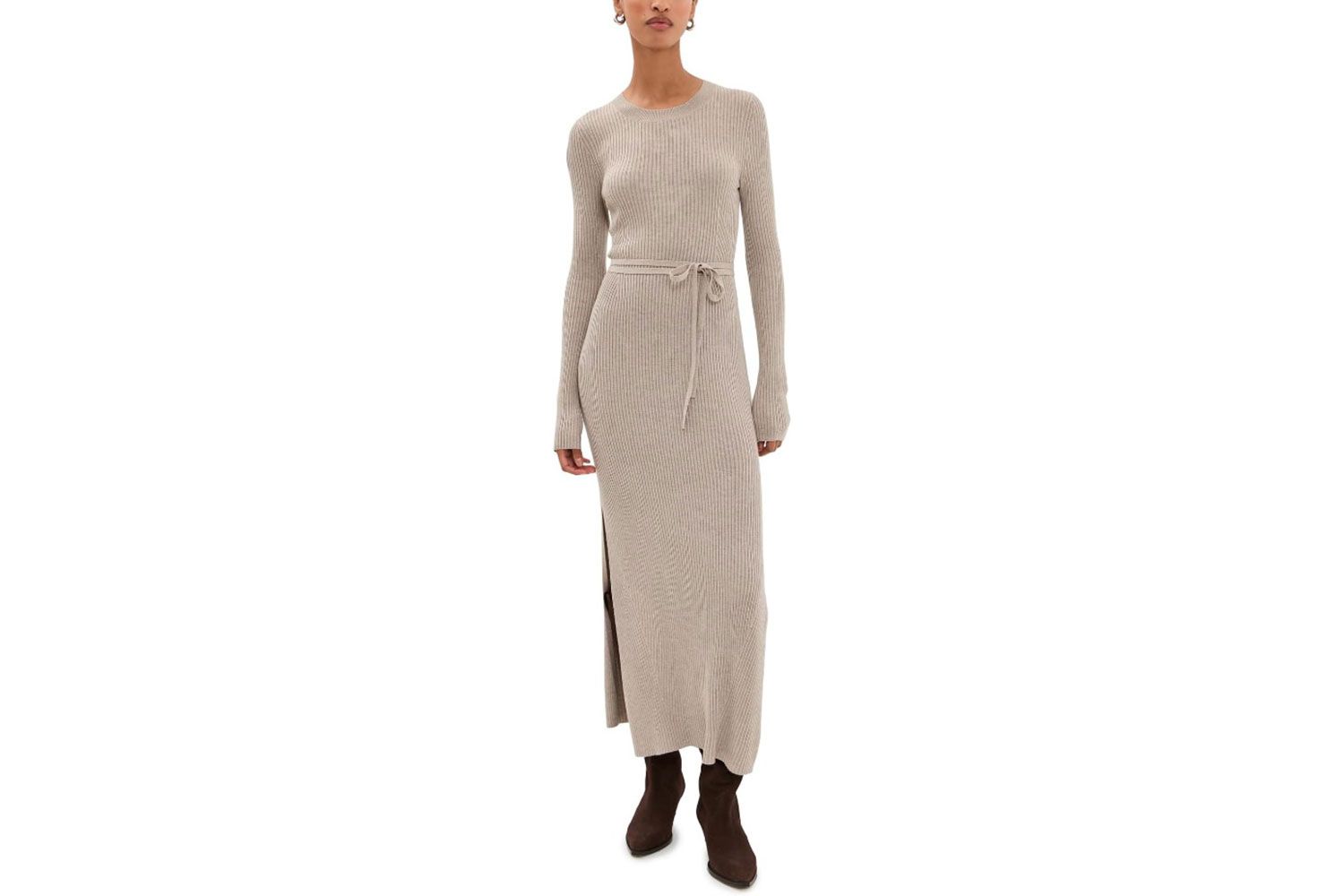 A person wearing a long sweater dress with a belt and boots standing against a white background