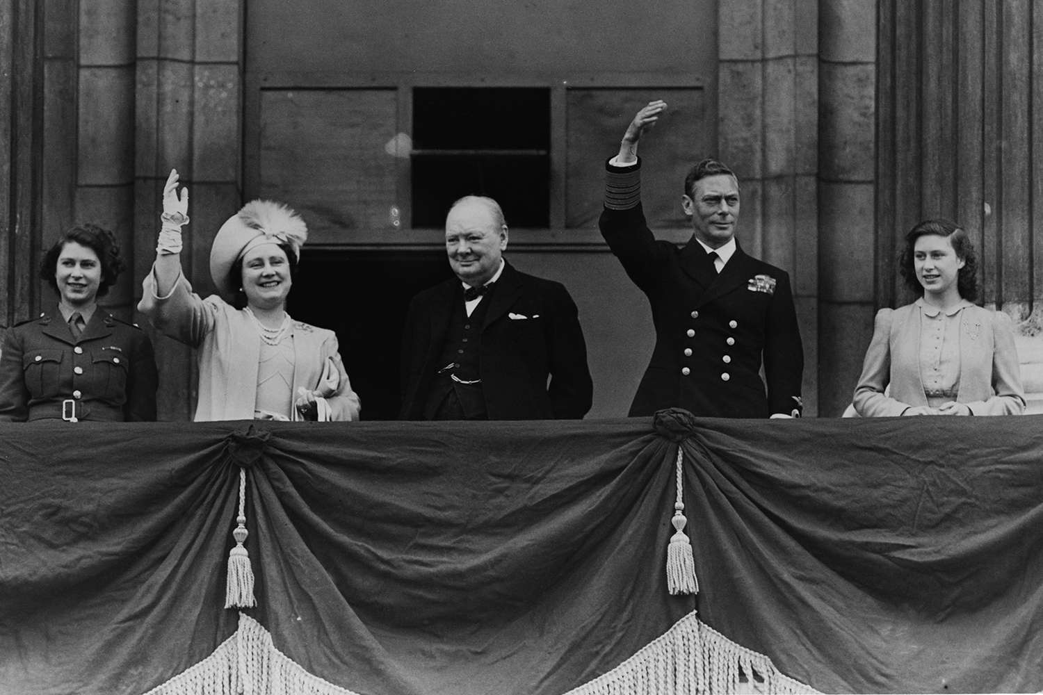 British prime minister Winston Churchill (1874 - 1965) (centre) with Queen Elizabeth, King George VI (1895 - 1952), Princess Elizabeth (left) and Princess Margaret Rose (1930 - 2002) waving from the balcony of Buckingham Palace during VE Day celebrations