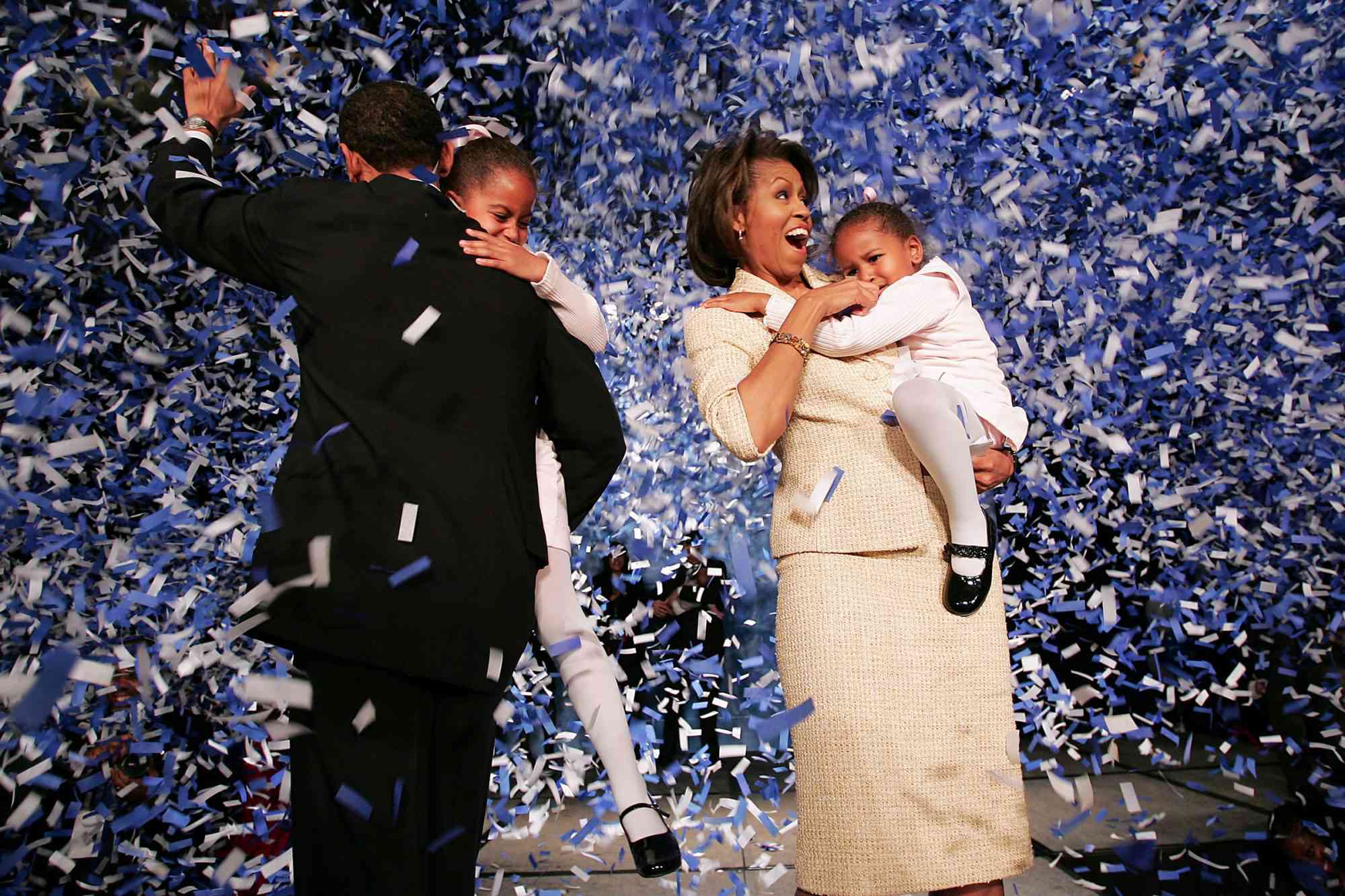 Barack Obama and Michelle Obama holding their daughters as they celebrate with supporters in Chicago on Nov. 2, 2004
