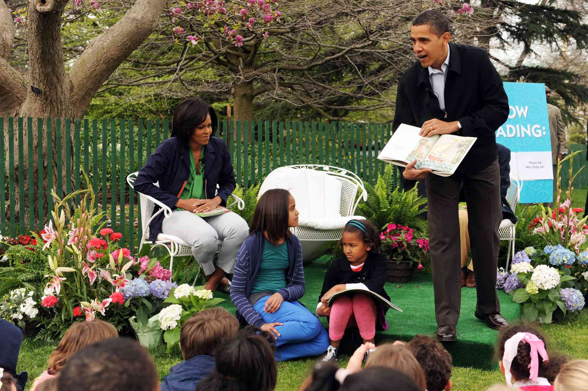 Barack Obama (right) reads a book to a group of children, as first lady Michelle Obama (left) and their daughters, Malia Obama (center left) and Sasha Obama (center right), sit with him during the annual White House Easter Egg Roll on April 13, 2009